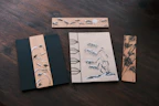 Elegant bookmarks and notebooks inspired by historical themes arranged on a wooden desk.