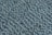 A close-up view of a textured surface featuring numerous smooth, oval stones embedded in concrete. The stones are dark grey and arranged in a pattern that creates a sense of movement and rhythm across the surface.