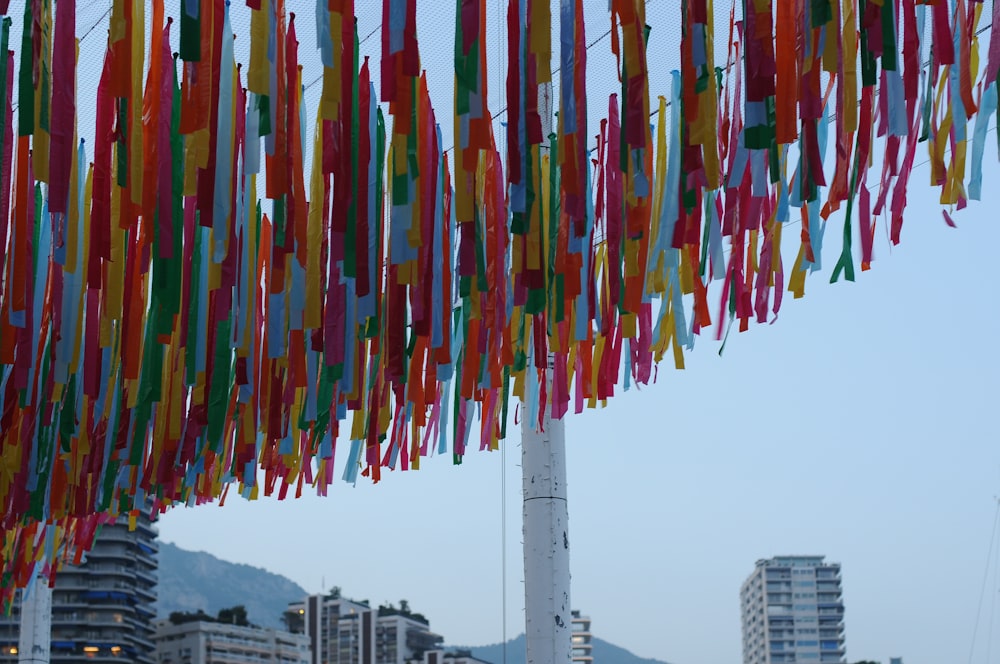 colorful streamers hanging from a pole in front of a city