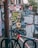 A vibrant urban street art scene with a mix of colorful graffiti and murals on a brick wall. The artwork includes abstract designs, cartoon characters like a mosaic dog, and various stickers and posters. A red and white bicycle is parked in the foreground, suggesting an urban environment.