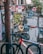 A vibrant urban street art scene with a mix of colorful graffiti and murals on a brick wall. The artwork includes abstract designs, cartoon characters like a mosaic dog, and various stickers and posters. A red and white bicycle is parked in the foreground, suggesting an urban environment.