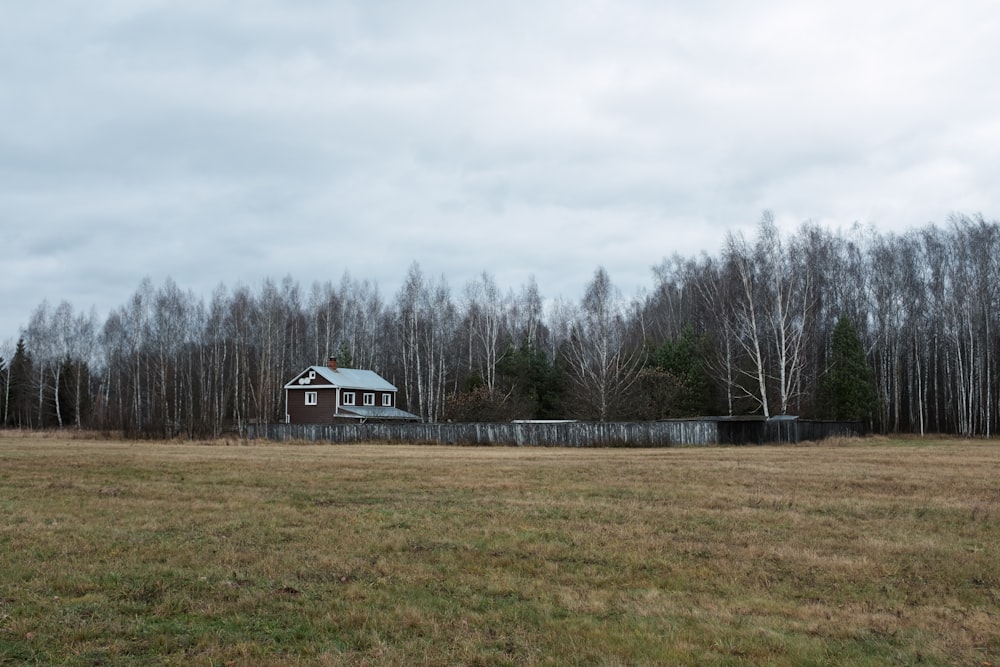 une maison dans un champ avec des arbres en arrière-plan