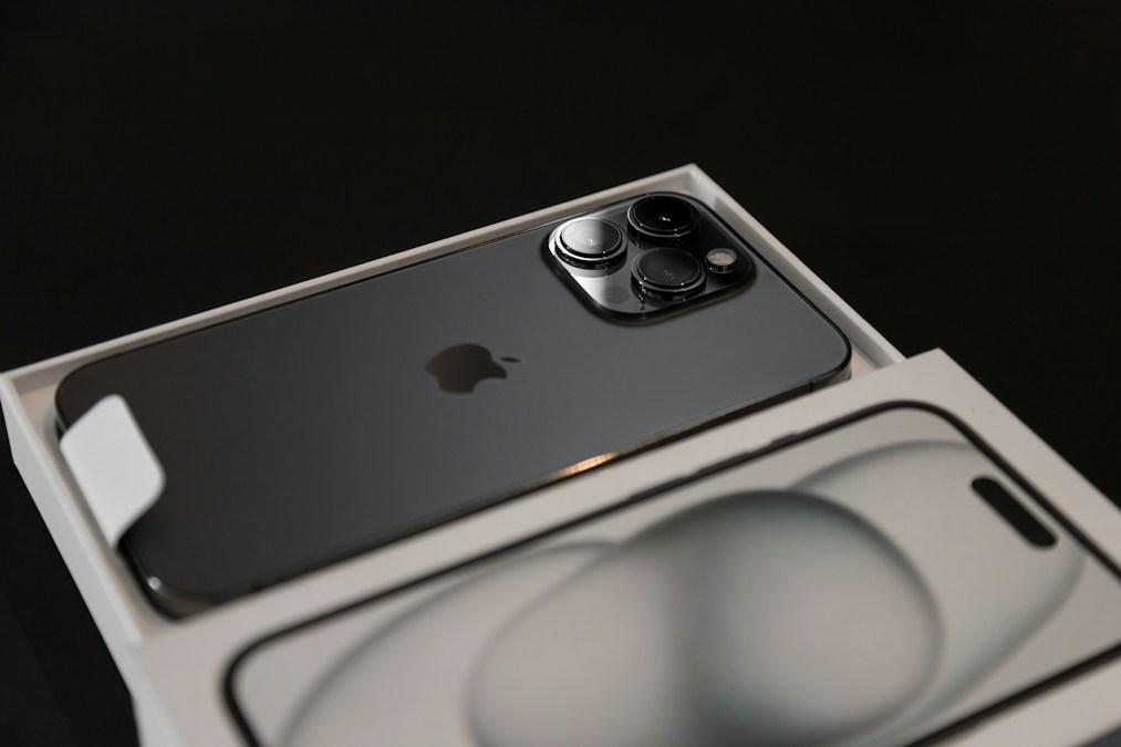 iPhone Pro gris d'une génération précédente dans sa boîte ouverte, sur fond noir (photo d'illustration, ce n'est pas un iPhone 18)