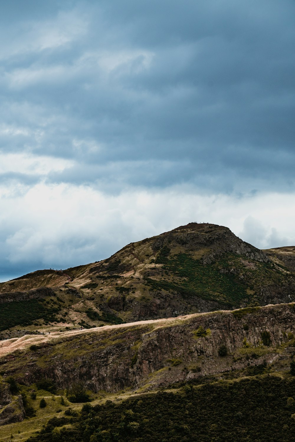 a hill with a road going through it under a cloudy sky