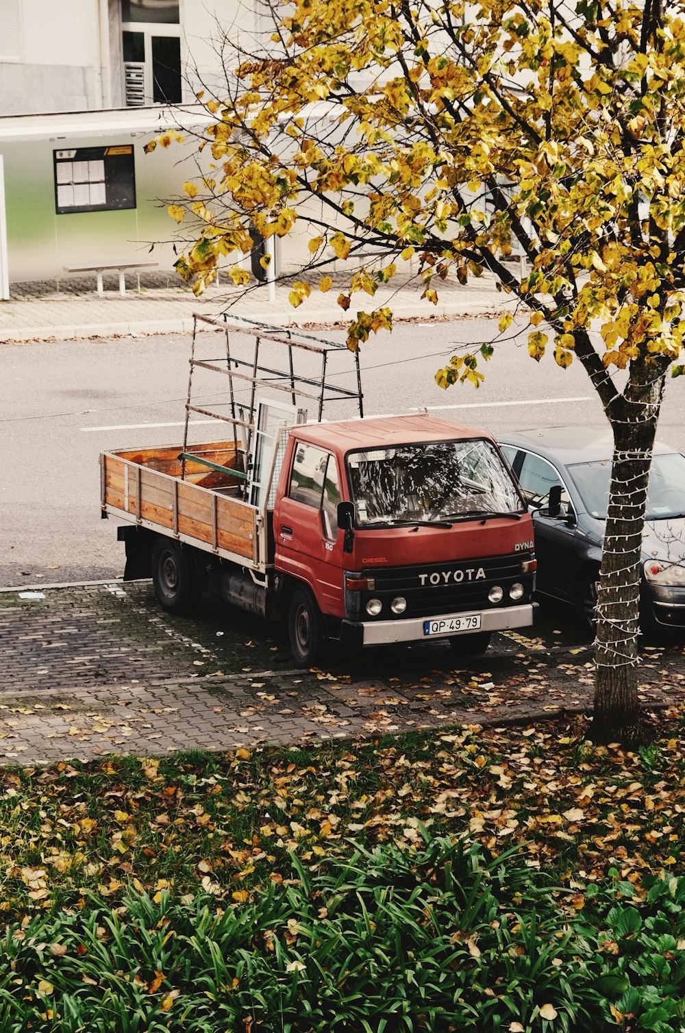 a red truck parked next to a tree