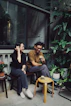a man and a woman sitting on a bench having drinks