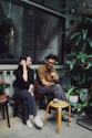 a man and a woman sitting on a bench having drinks