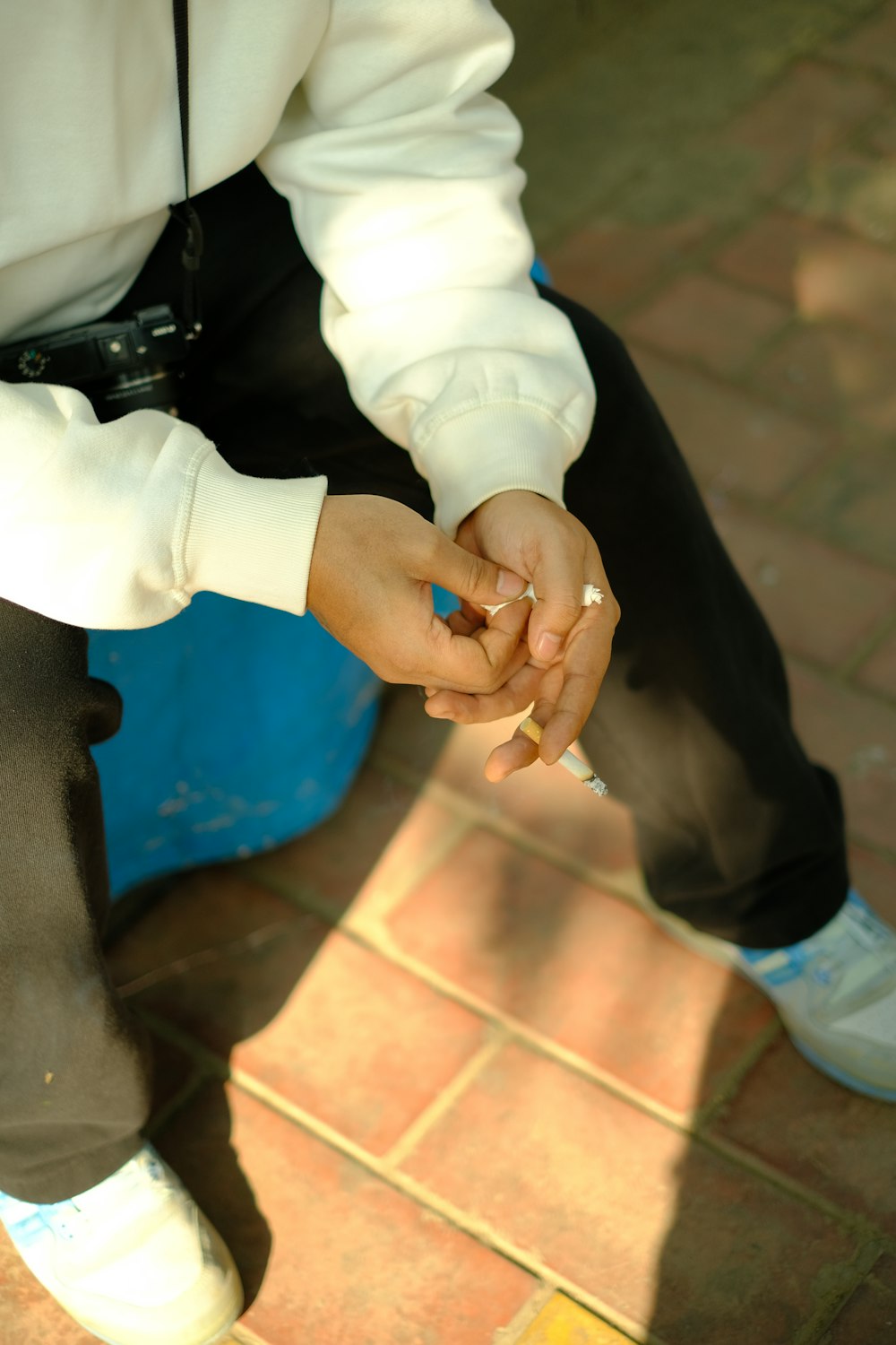 a person sitting on the ground with a cigarette in their hand