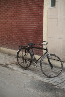 A mark backpack casually placed beside a vintage bicycle on a cobblestone street.