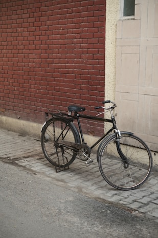 A mark backpack casually placed beside a vintage bicycle on a cobblestone street.