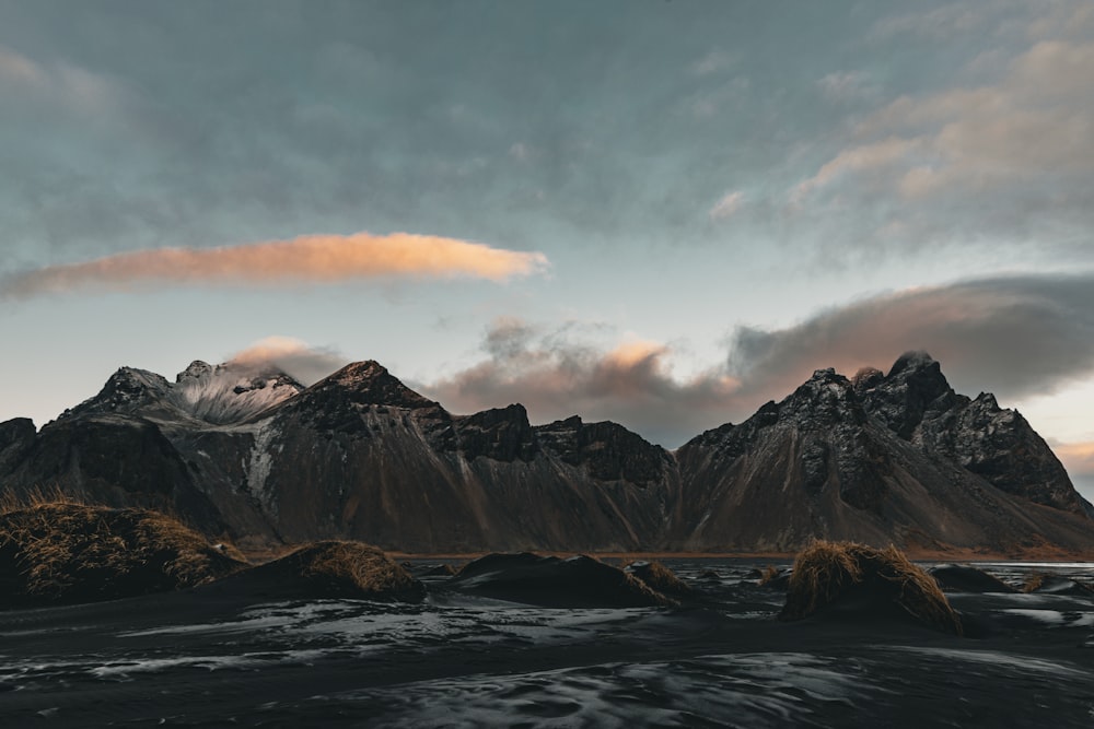 a group of mountains with a cloudy sky in the background