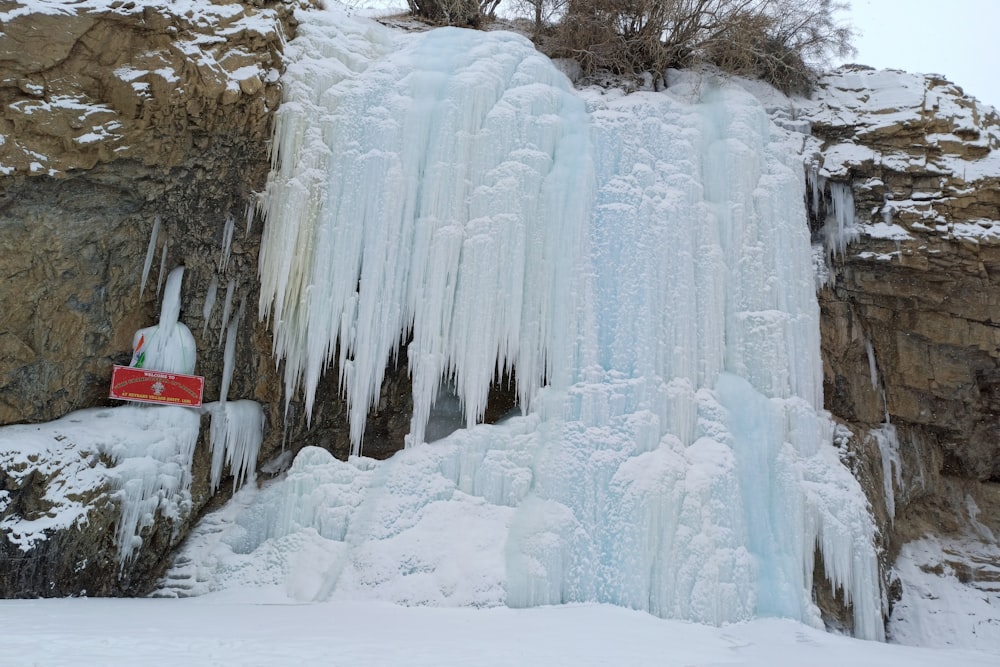 a frozen waterfall with a red sign on it