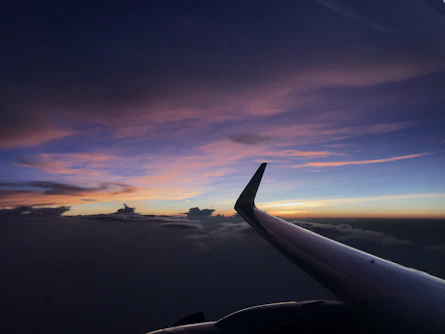 View of airplane wing flying over a beautiful sunset sky.