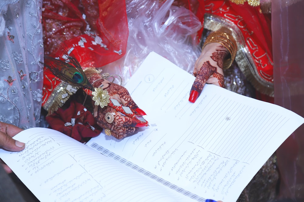 a person holding a book with henna on their hands