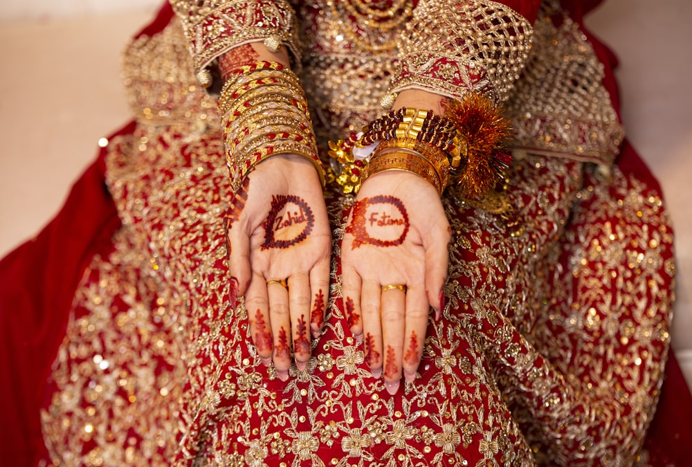 a woman in a red and gold dress holding her hands with the word love painted