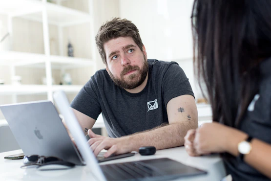 a man and a woman sitting at a table looking at a laptop