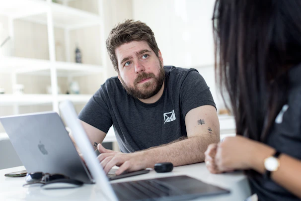 a man and a woman sitting at a table looking at a laptop