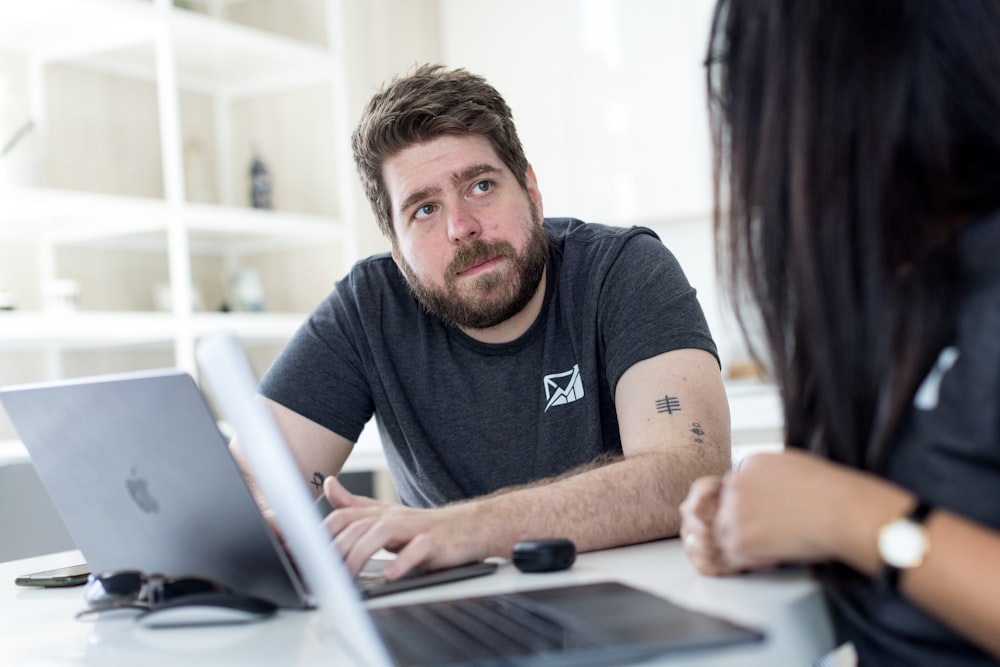 a man and a woman sitting at a table looking at a laptop