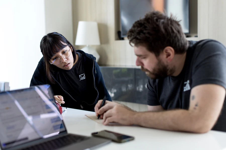 A specialist sitting with a client at a table, reviewing loan documents on a laptop