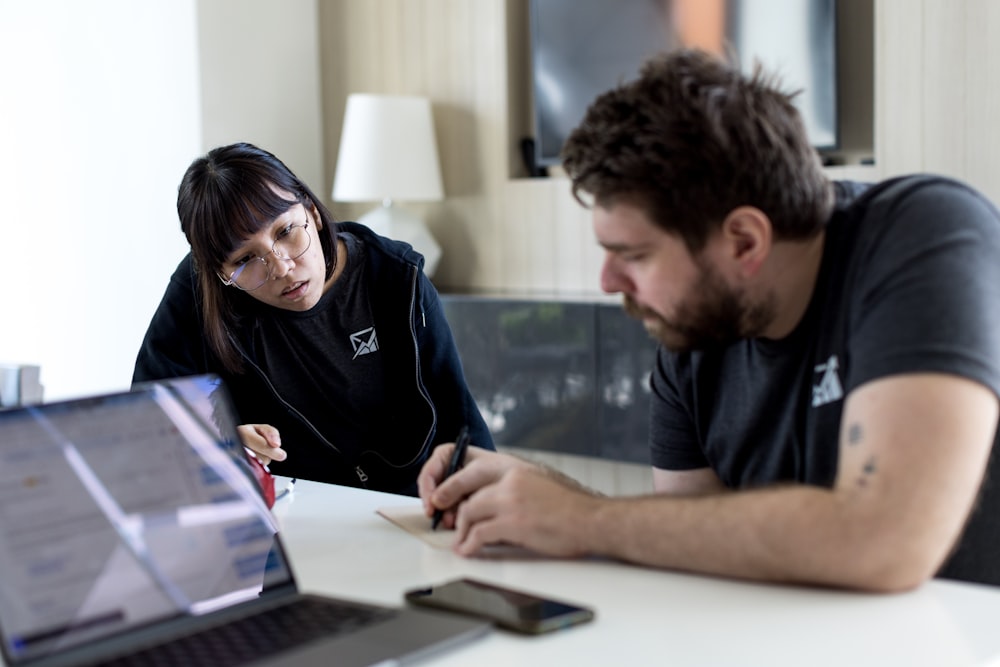 a man and a woman sitting at a table with a laptop