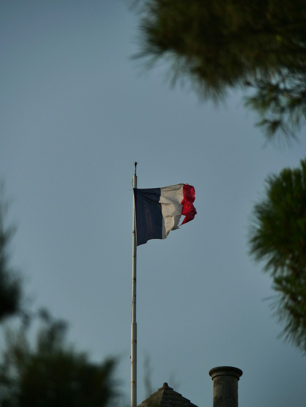 a flag flying on top of a roof next to a tree