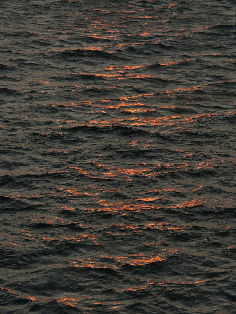 a large body of water with a sunset in the background