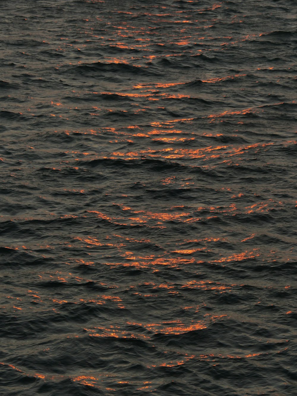 una gran masa de agua con una puesta de sol al fondo