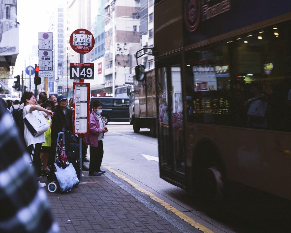 a group of people standing on a sidewalk next to a bus