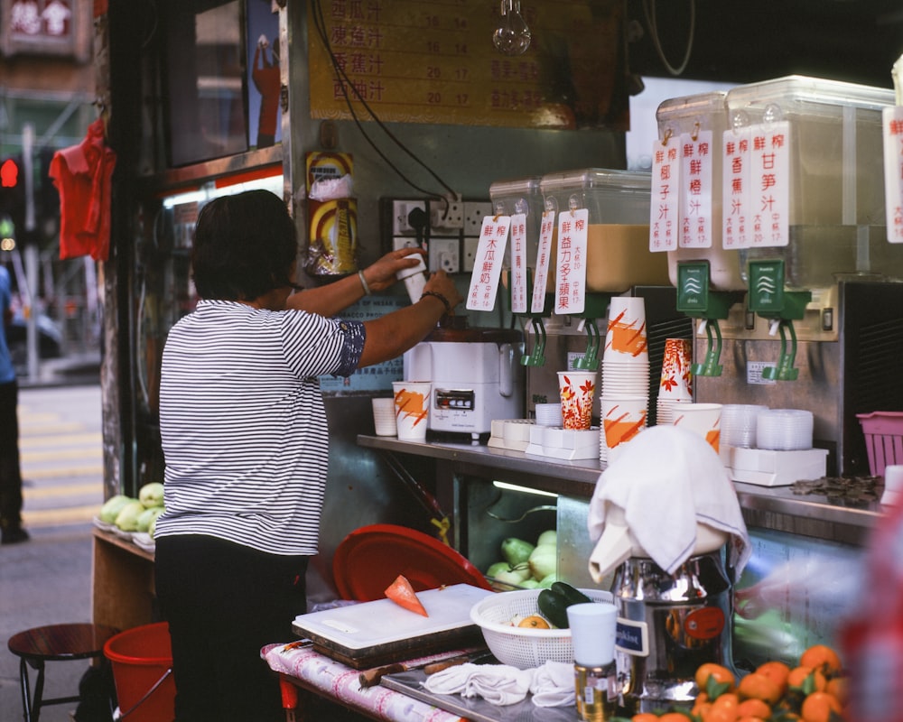 a woman standing at a food stand preparing food
