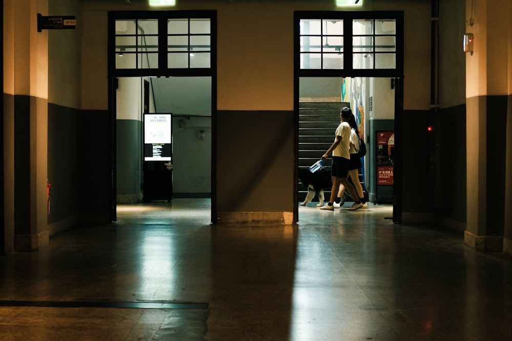 a woman walking down a hallway with a suitcase