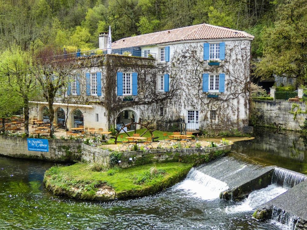 a building with blue shutters next to a river