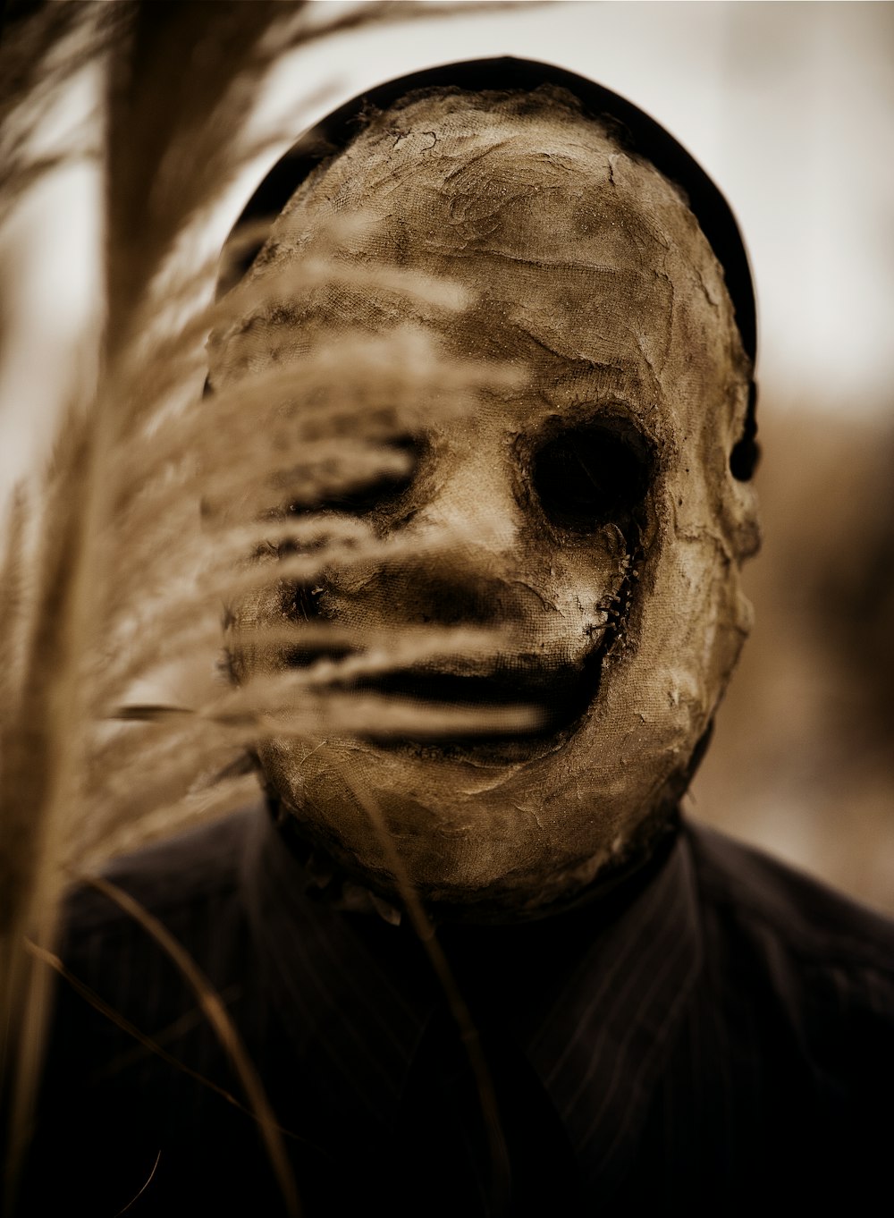 a man wearing a creepy mask in a field