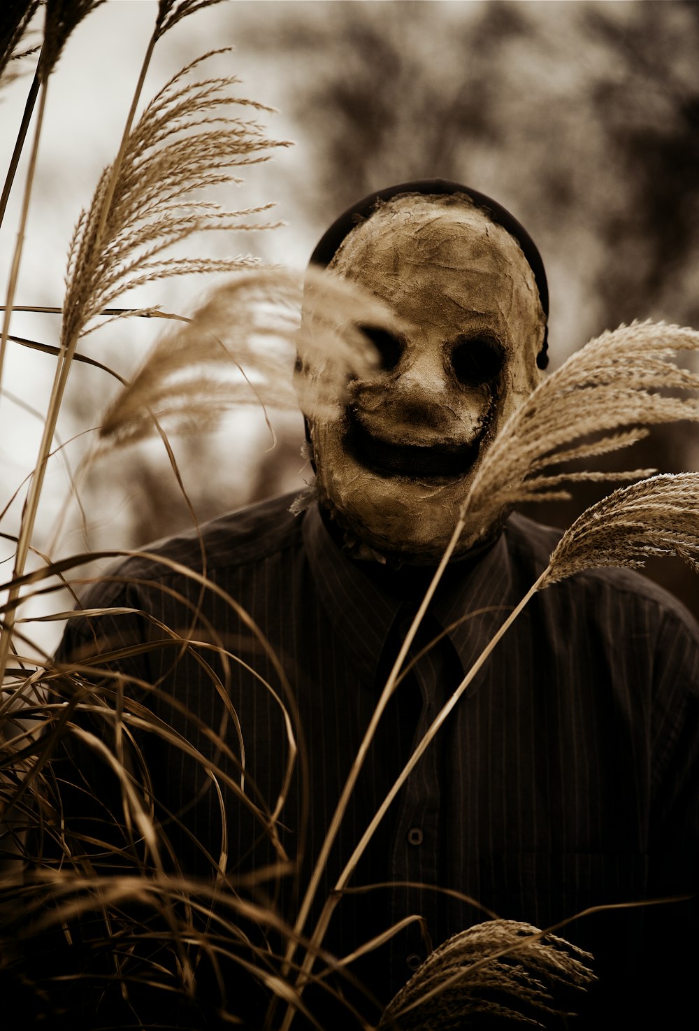 Un hombre con una máscara espeluznante parado en la hierba alta