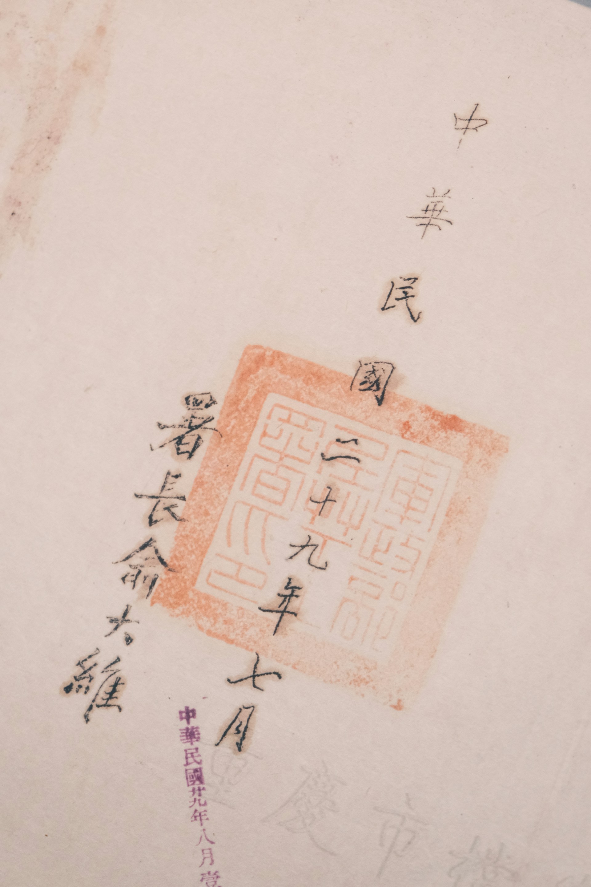 The image features Chinese calligraphy with a red stamp seal, showcasing traditional characters on a light-colored paper. The text is arranged vertically and accentuated by the vivid red of the stamp.