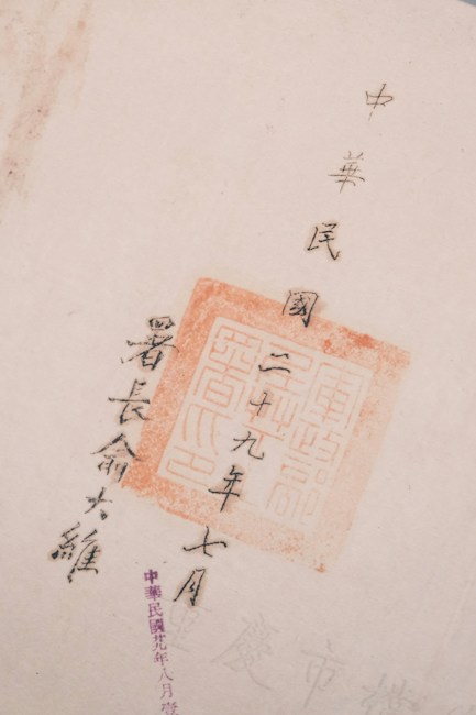 The image features Chinese calligraphy with a red stamp seal, showcasing traditional characters on a light-colored paper. The text is arranged vertically and accentuated by the vivid red of the stamp.