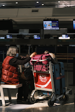 a woman sitting in a chair next to a luggage cart