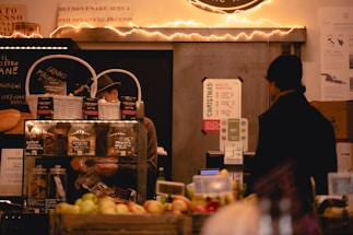 A cozy rustic market stall displaying fresh dairy products, pickles jars, and baked goods.