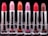 A row of six lipsticks in varying shades displayed against a black background. The lipsticks are housed in metallic silver tubes, with colors including red, pink, orange, and brown. Each lipstick has a distinct color, creating a gradient effect.