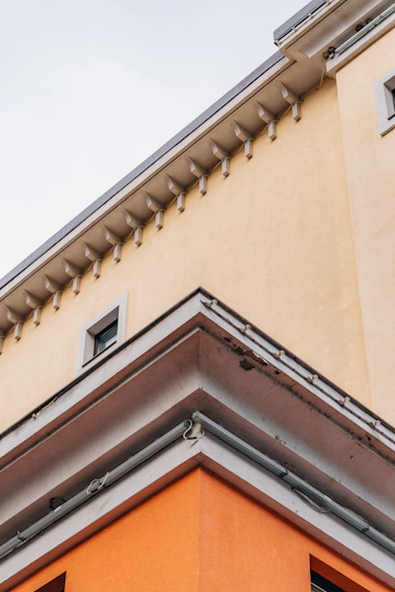 Close-up of a white EPS foam cornice with a smooth, reinforced coating installed on a modern building facade.