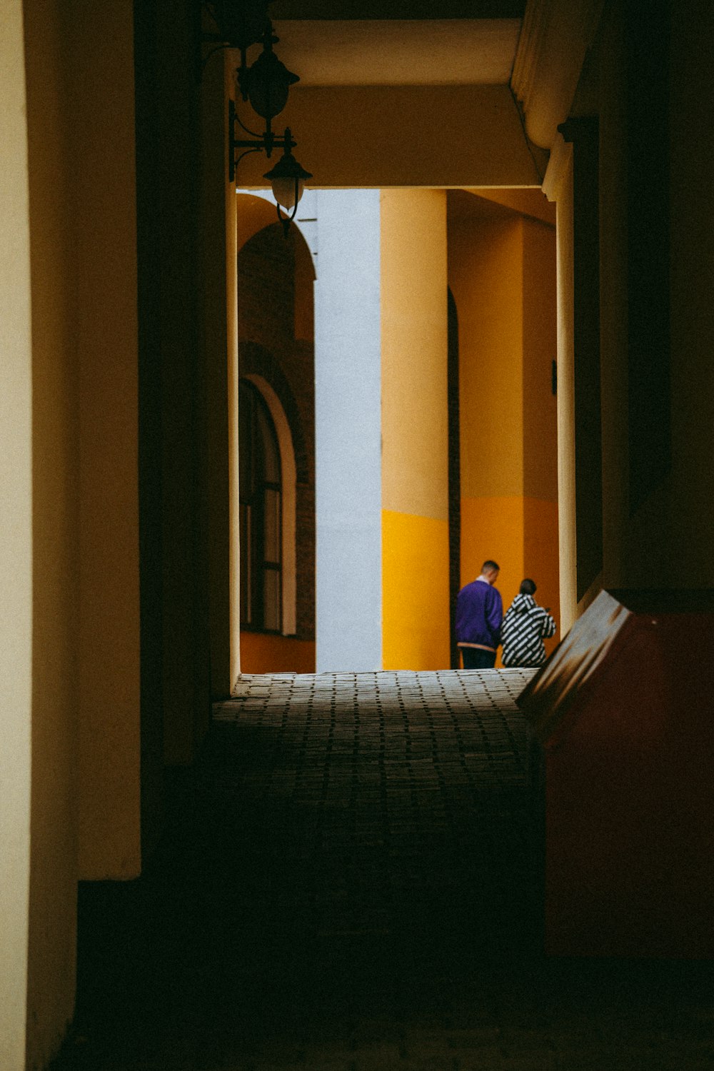 two people sitting on a bench in a hallway