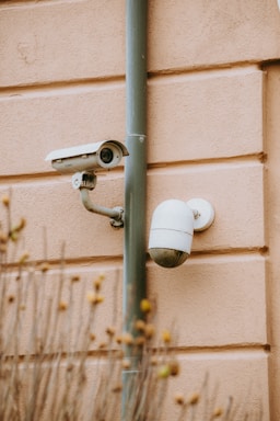 A sleek Hikvision CCTV camera mounted on an exterior wall under soft daylight.