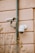 Two surveillance cameras mounted on an exterior wall made of pinkish-beige textured material. One camera is dome-shaped while the other is cylindrical, attached to a vertical metal pole.