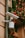 A security camera is mounted on an exterior wall with festive holiday decorations. Green garlands adorned with red and gold ornaments and small bird decorations hang nearby, enhancing the holiday atmosphere.