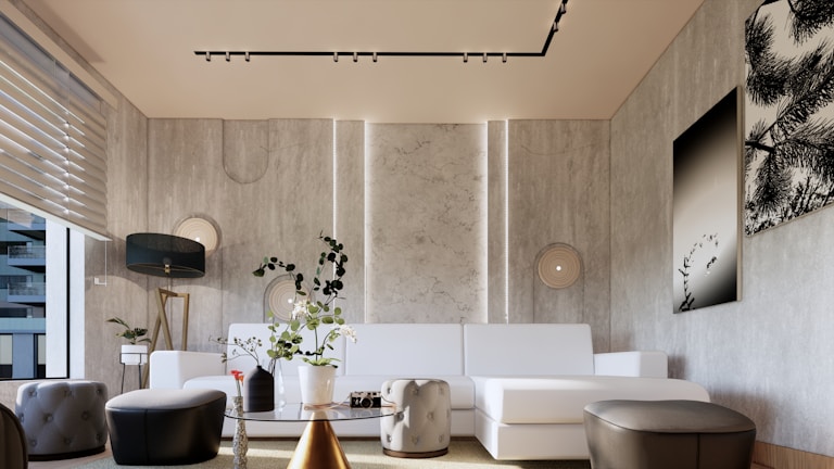 A modern living room with a minimalist design, featuring a large white sectional sofa against a textured wall. There is a black floor lamp with a gold stand and a few round poufs and a small table with a vase holding green plants. The walls are decorated with framed art that contains black and white nature imagery. Light filters through horizontal blinds on the left, creating a bright and airy atmosphere.