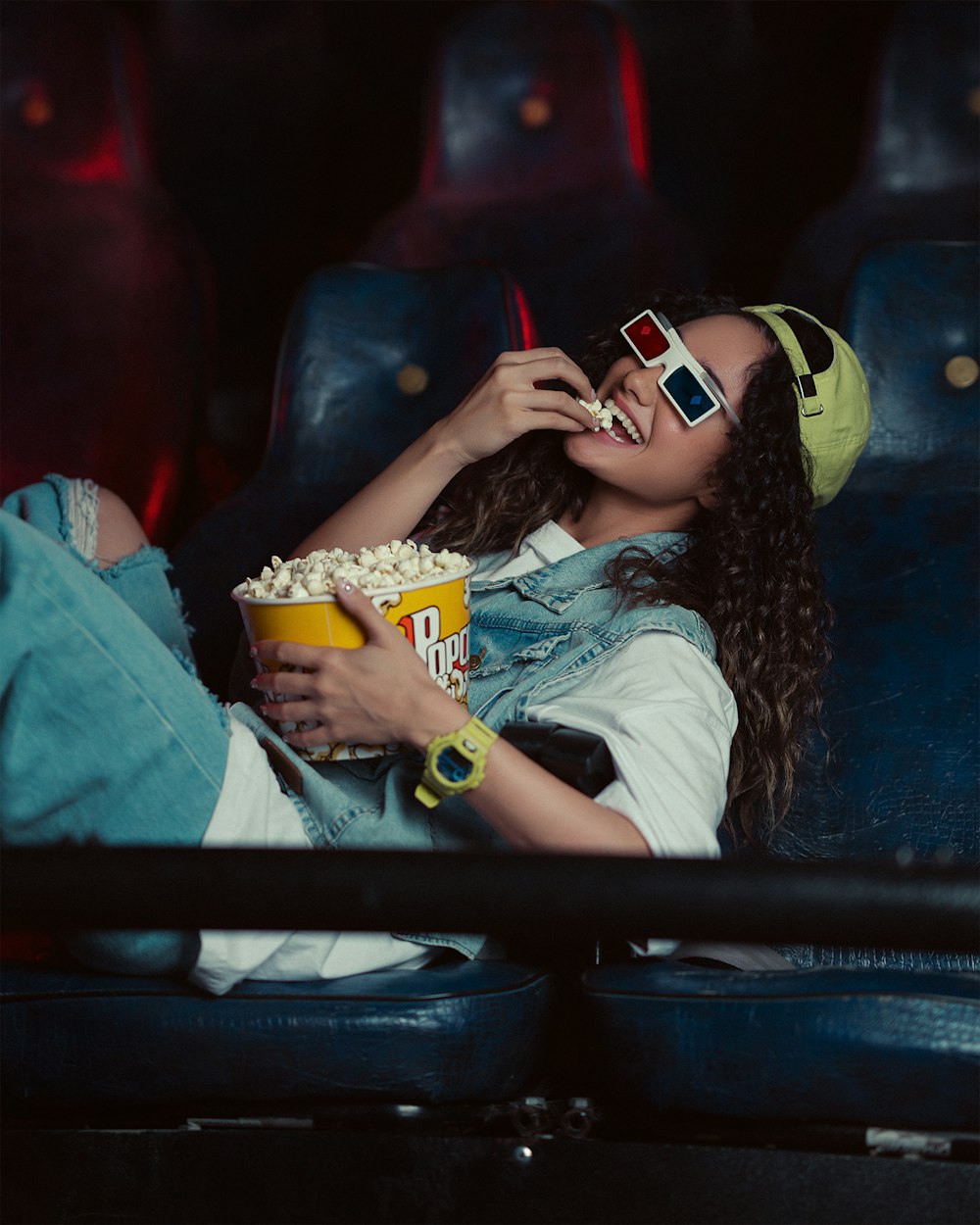 a woman sitting in a chair eating popcorn and watching a movie