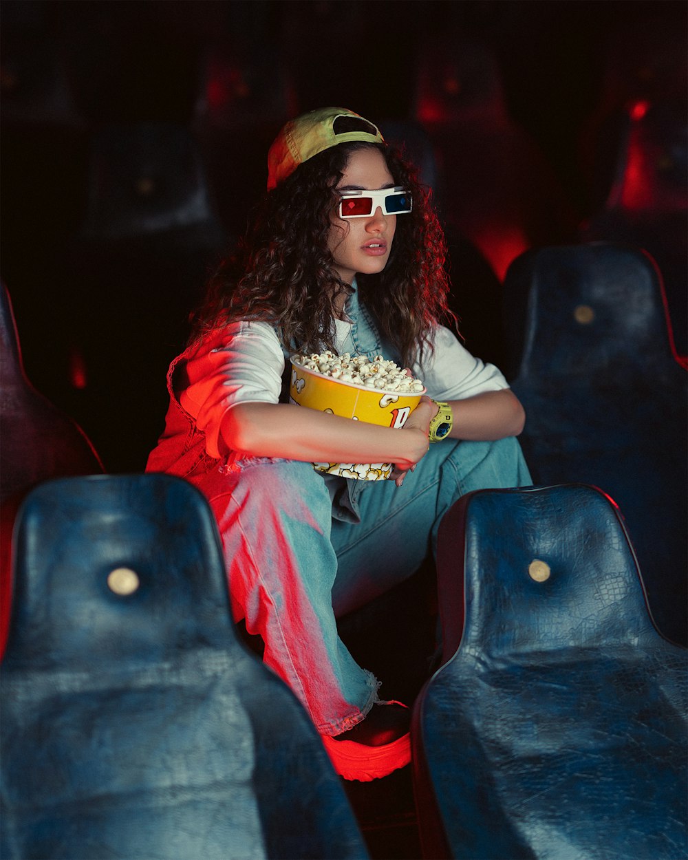 a woman sitting in a movie theater holding a bowl of popcorn