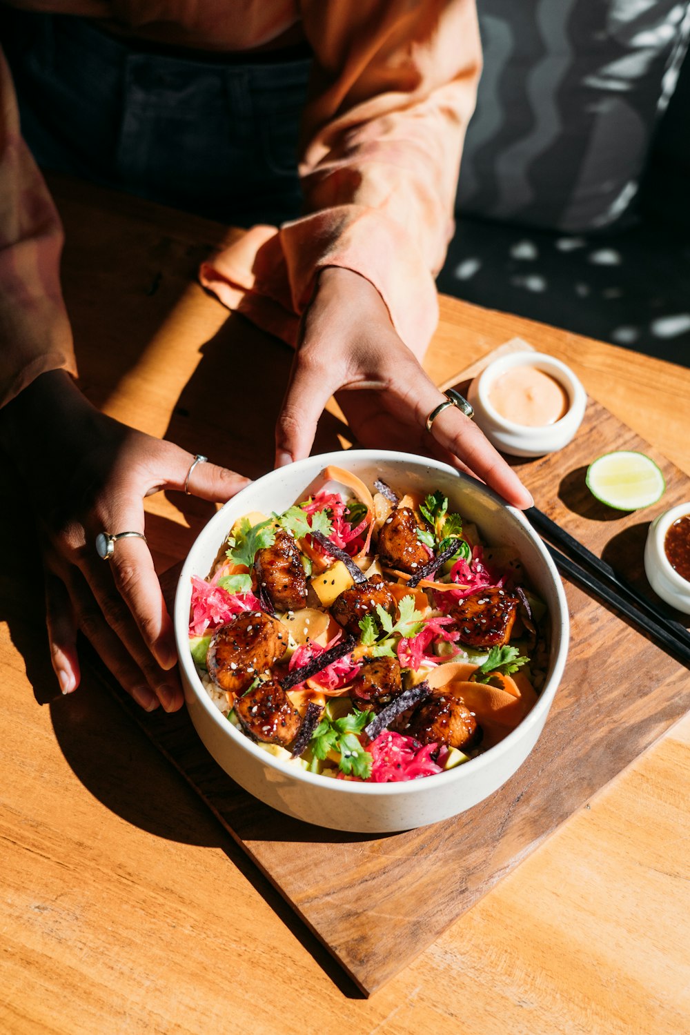 a person holding a bowl of food on top of a wooden table