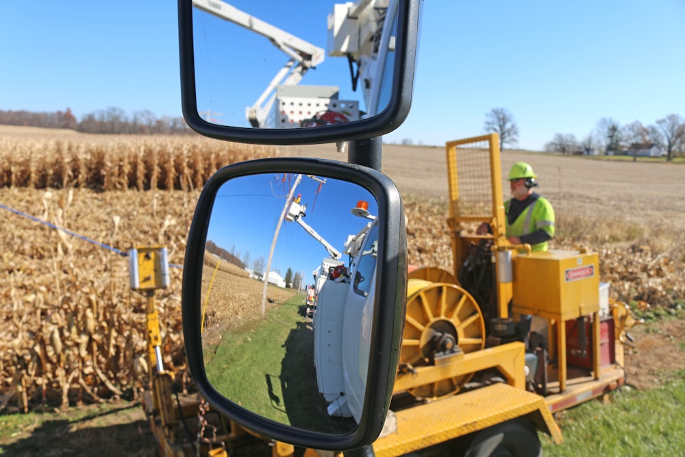 a person in a tractor is reflected in a rear view mirror