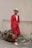 a man in a red suit holding a brown bag