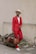 a man in a red suit holding a brown bag